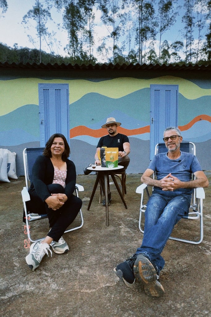 Talles sits with his parents in front of the farmhouse painted with a mountain landscape