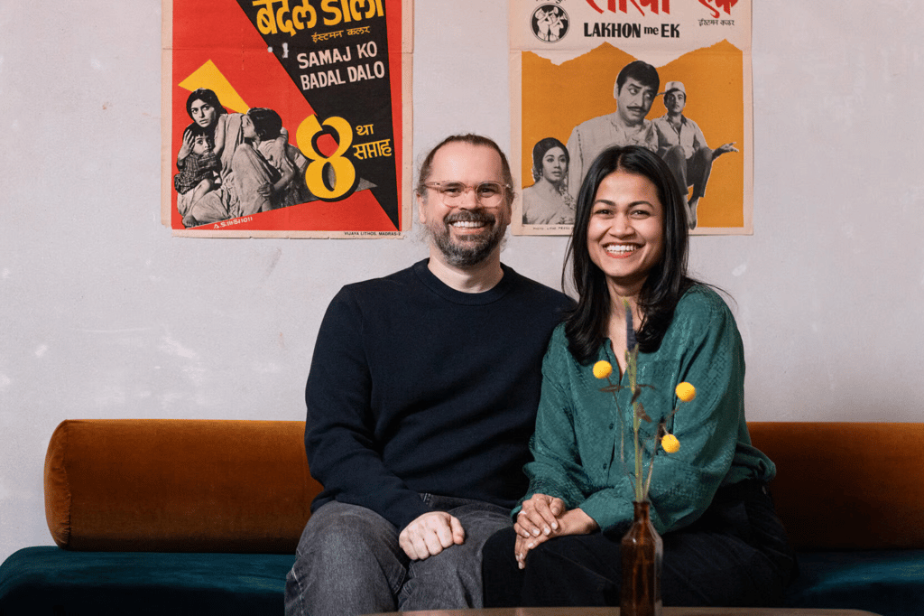 Mota Italic's two founders smiling side by side beneath vintage Indian film posters.