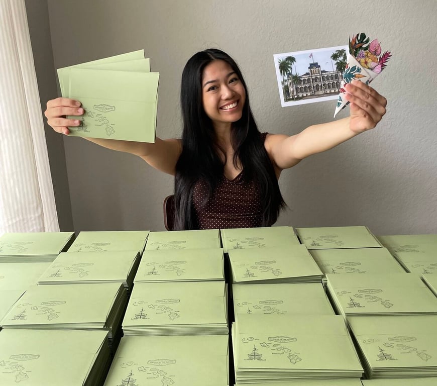 Trinity Shiroma with stacks of subscription envelopes ready to ship to customers.
