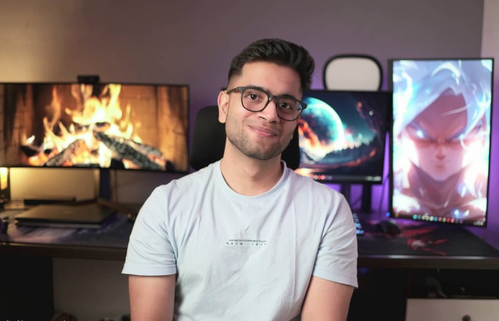 Ansh Bhawnani, founder of Bitten Tech, at his desk in front of monitors displaying a fireplace and anime artwork