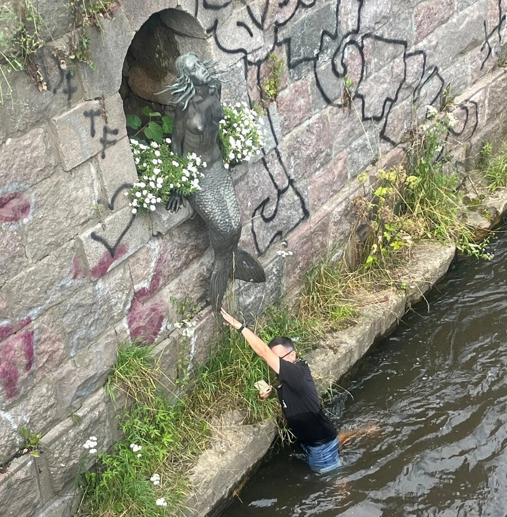 Camo team member touching the mermaid statue's tail in Uzupis