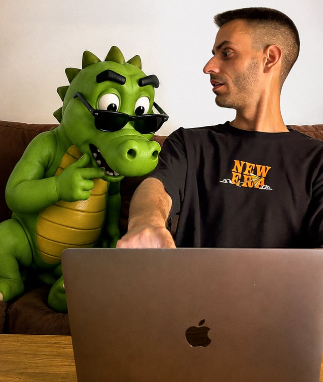 Manuel Ferre on a sofa next to a large green dinosaur figure in sunglasses, the mascot of his clothing brand Bribón, pointing at his laptop