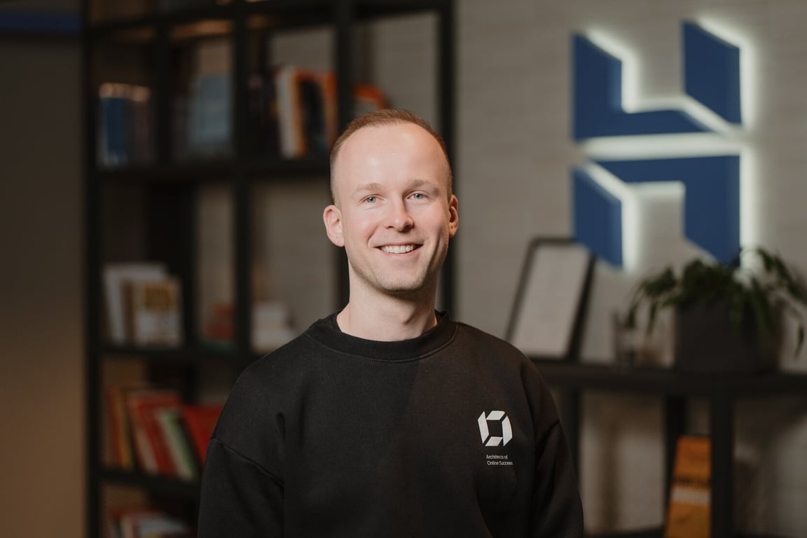 emilis-strimaitis Portrait of Emilis Strimaitis, Head of Product Innovation at Hostinger, smiling in forefront of the Hostinger logo