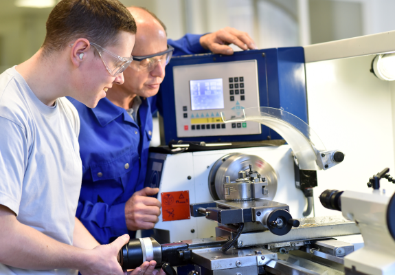 작업자가 CNC 기계를 점검하고 있는 장면