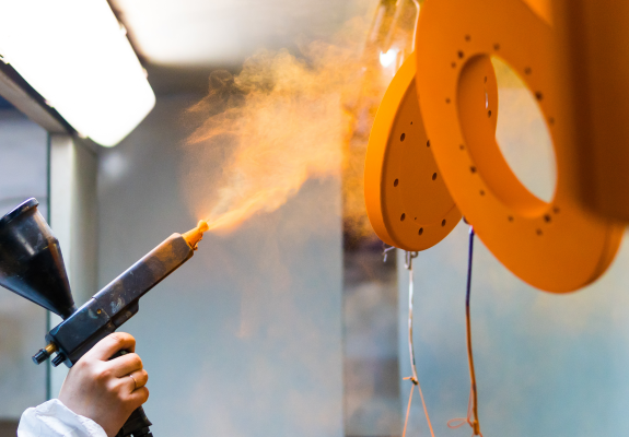 밝은 주황색의 파우더(분체도료)를 코팅하고 있는 장면