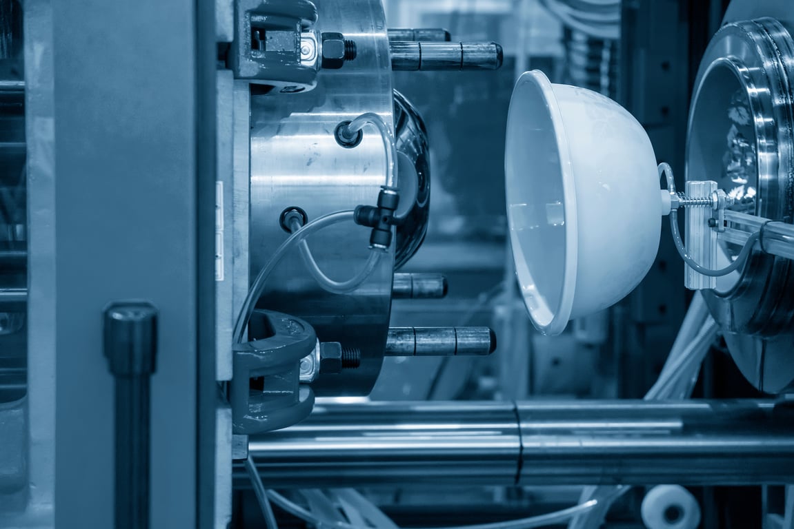 플라스틱 파트가 로봇팔에 의해 사출 성형 기계 사이에 위치한 모습