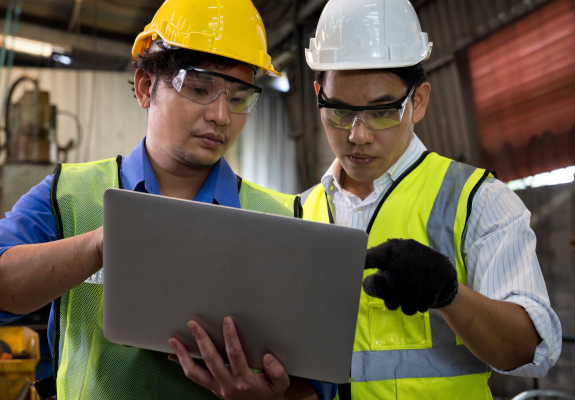 OEM 정의 및 개념 설명.  공장에서 두명의 작업자가 작업 지시 사항에 대한 이야기를 나누고 있다.