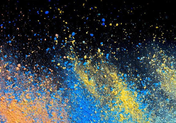 주황, 파랑, 노랑의 삼색 파우더가 검은색 배경에 흩뿌려져있다.