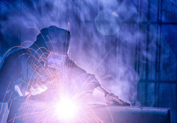 스텐 파이프를 용접하는 장면 주광색 빛의 불꽃이 튀기고 보호마스크를 쓴 작업자가 직접 용접을 하고 있다