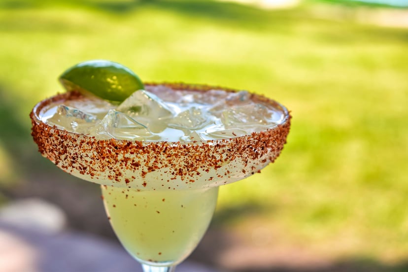 A Margarita cocktail served with ice and a wedge of lime