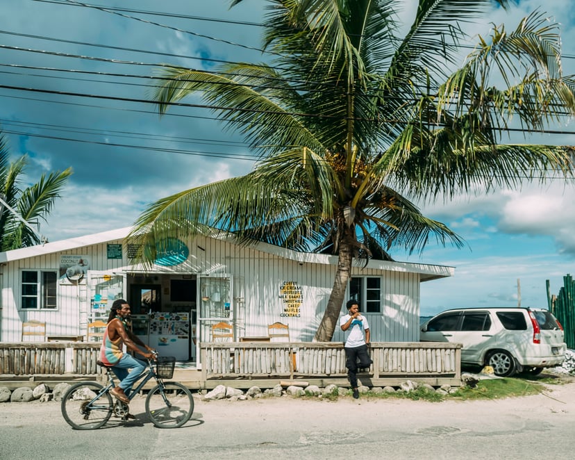 A man on a bicycle cycles past a wooden shop in Jamaica