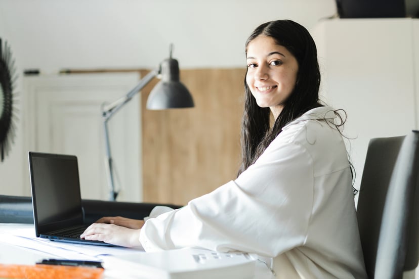 Young woman smiling as she uses her laptop
