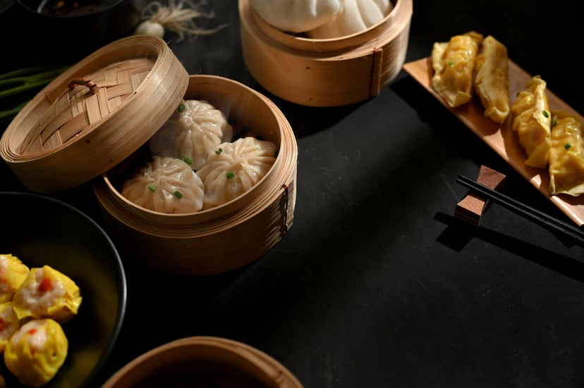 Dim sum including steamed buns in a bamboo steamer and fried dumplings