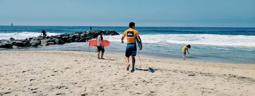 a man with a boogie board wearing a Quiksilver t-shirt running along a beach
