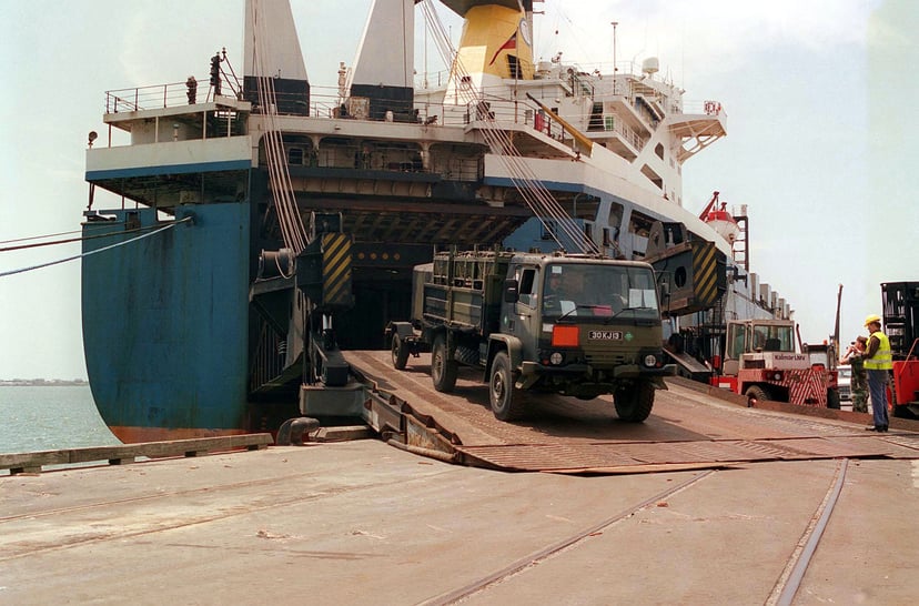 An army truck rolling off a car carrier vessel
