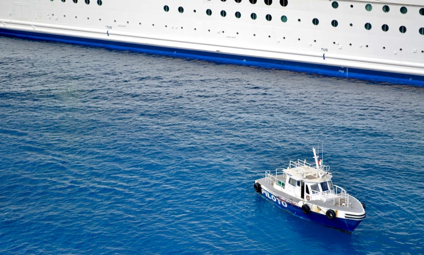 a pilot boat alongside a much larger vessel