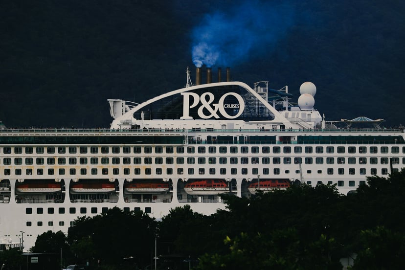 A P&O cruise ship docked behind some trees