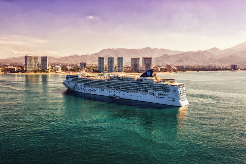 A Norwegian Cruise Lines cruise ship sailing past  beach resort at dusk