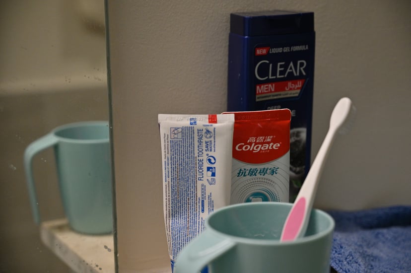 Colgate toothpaste and a toothbrush in a mug on a bathroom counter