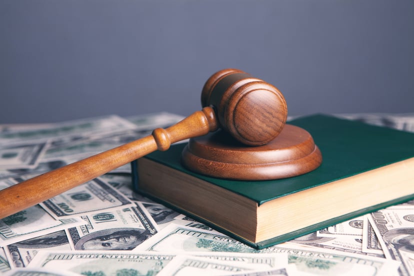 A judge's gavel on a book with bank notes underneath them