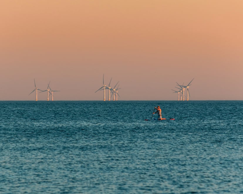 an offshore wind farm under a pink sky