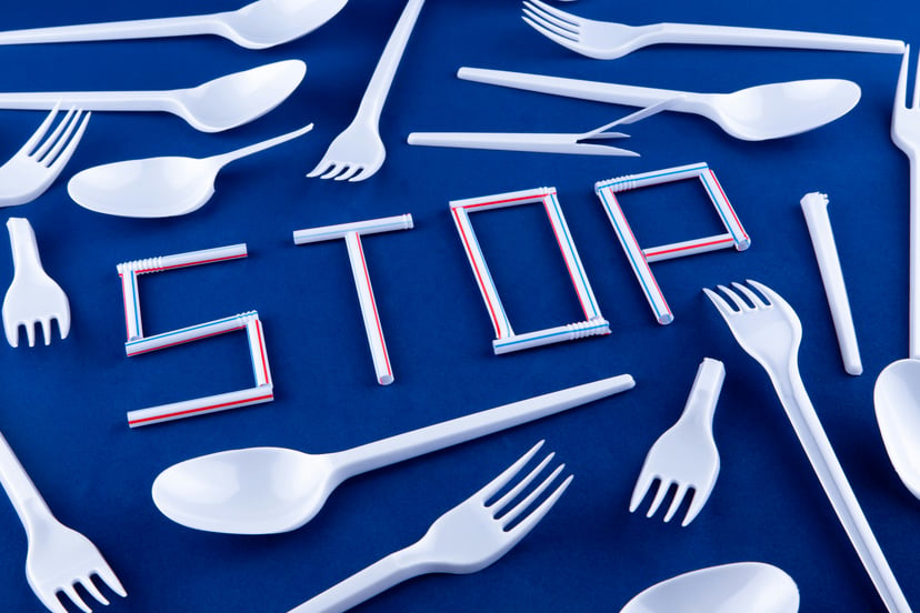 disposable plastic cutlery and plastic straws spelling the word 'stop'
