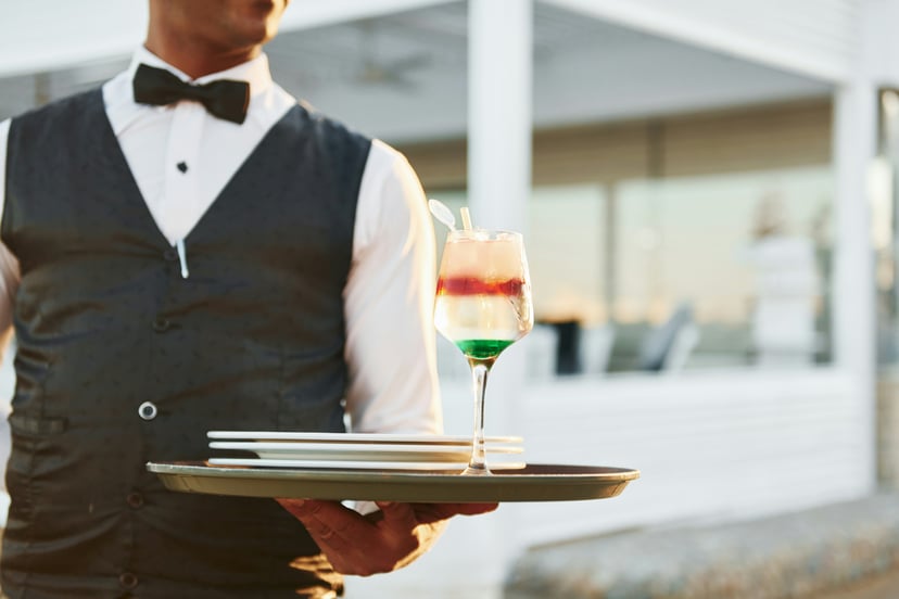 A butler offering a cocktail on a platter