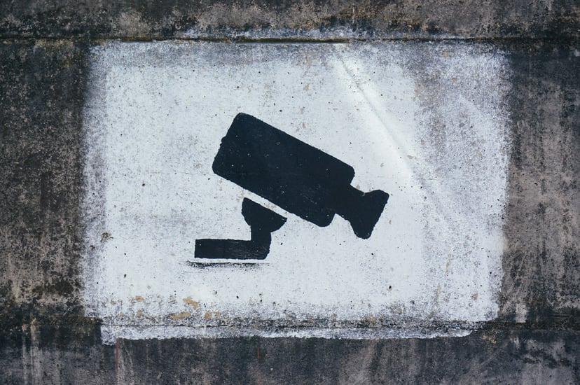 A stenciled CCTV camera on a wall