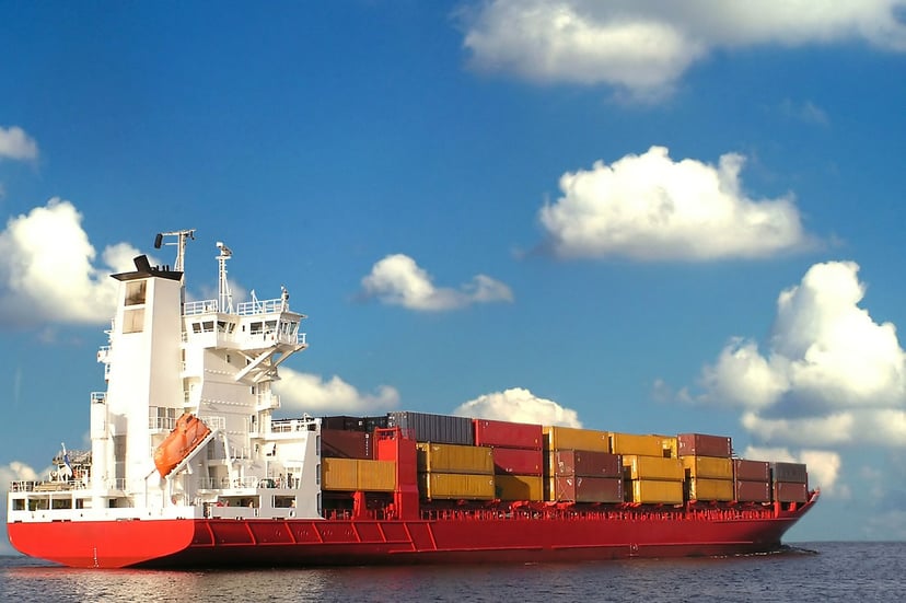 a small cargo ship sailing under a blue cloudy sky