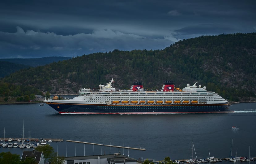 The Disney Magic cruise ship sailing near the shore under a dark sky