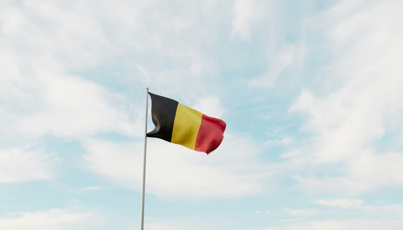 The Belgian flag flying against fluffy white clouds