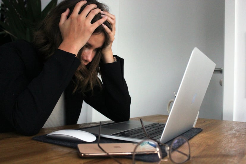 Frustrated woman with her head in her hands using a laptop