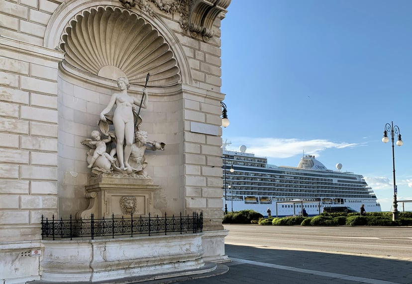 A Regent seven Seas cruise ship docked behind a stone statue