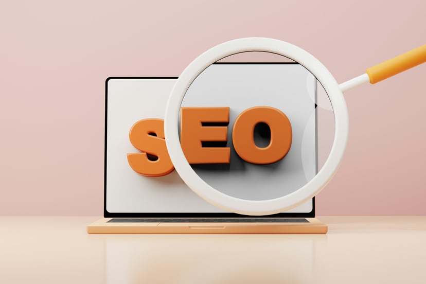 The letters SEO on  laptop screen with a magnifying glass in front of them
