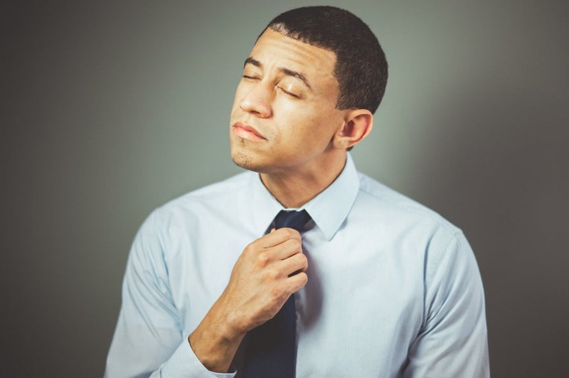 An uncomfortable looking man loosening his tie