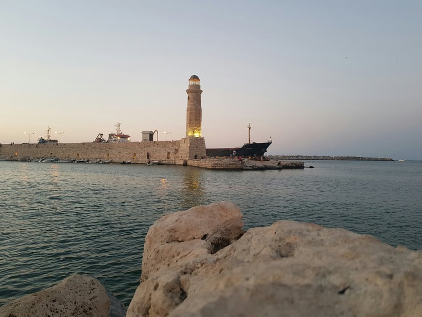 A lighthouse and cargo ship on the shoreline of Crete