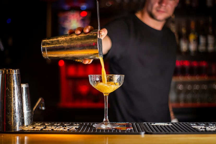 A male bartender pouring a cocktail