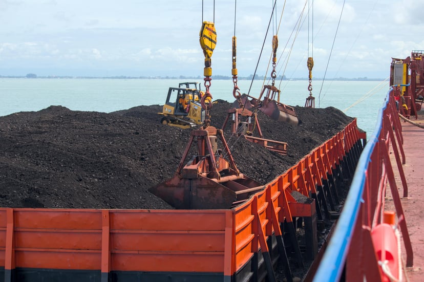 soil being loaded on to a cargo ship using bucket cranes