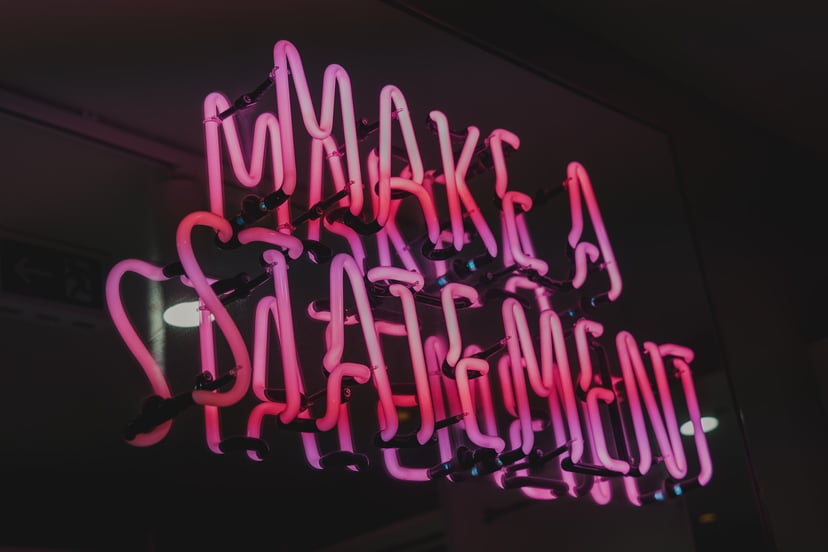 purple and pink neon sign saying 'make a statement'