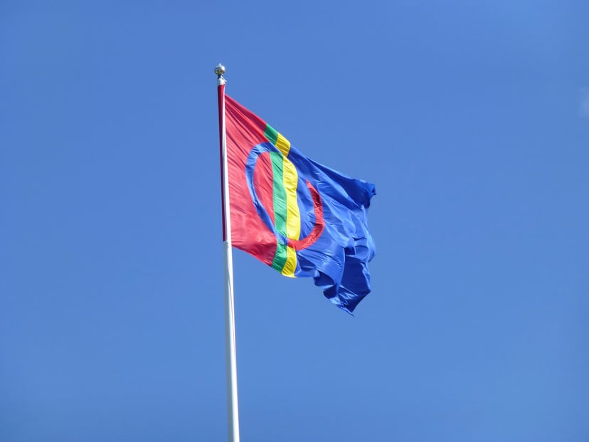 The Sami flag flying against a blue sky
