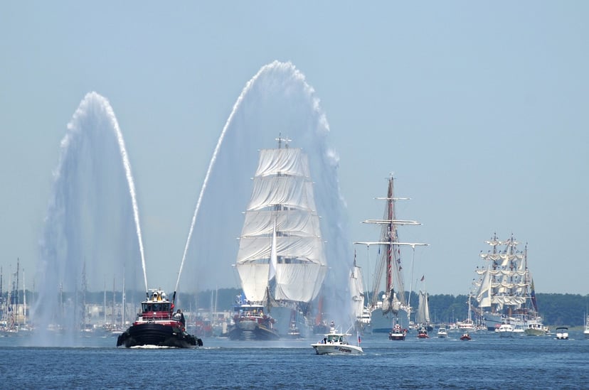 a fireboat welcoming a tall ship
