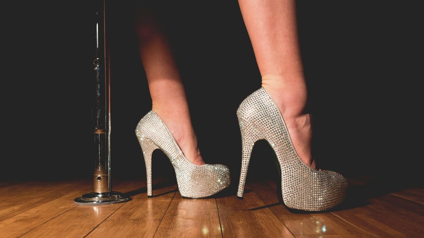A pole dancing pole and a woman's feet in a pair of high heels