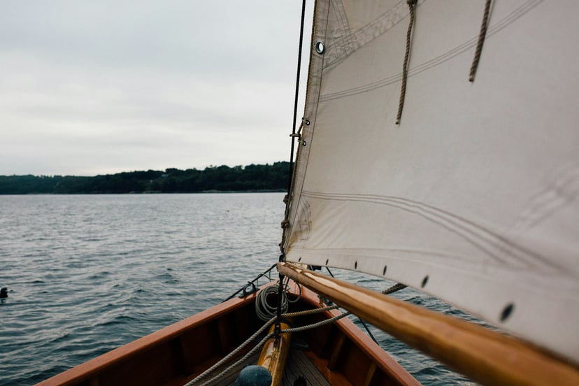 the bow and sail of a wooden sailing dinghy