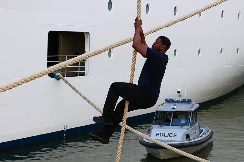 A man climbing the mooring rope of a cruise ship