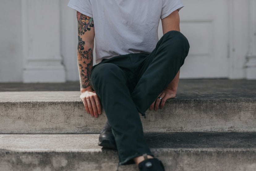 A man with a tattooed arm sitting on some stone steps