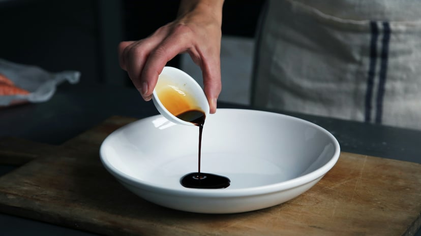 A chef pouring soy sauce into a bowl