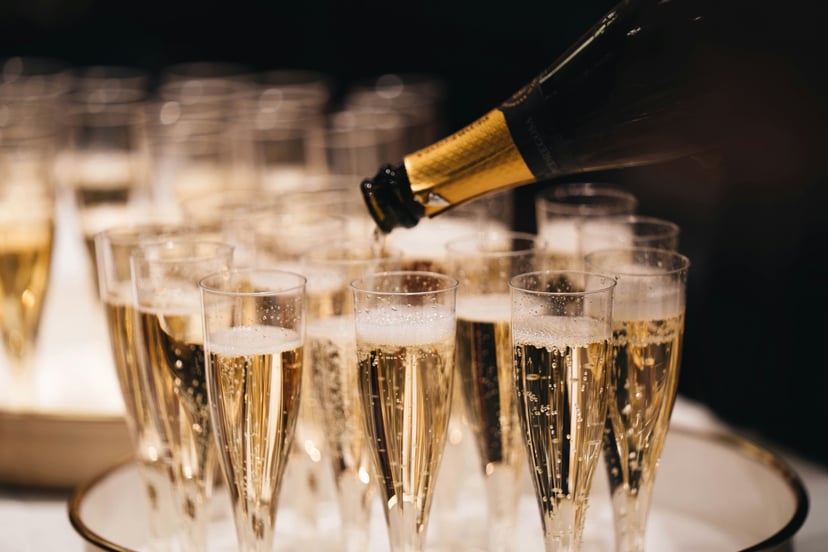 A bottle of Champagne being poured into flutes