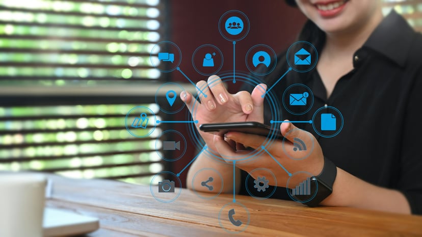 smiling woman using phone that has icons popping out of the screen