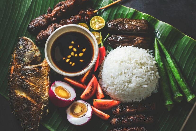 Filipino food including fish, rice and egg on a palm leaf plate