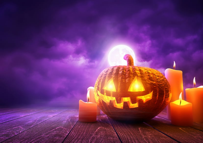 A jack-o-lantern and candles under a full moon